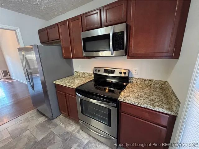 a kitchen with stainless steel appliances granite countertop a stove microwave and refrigerator