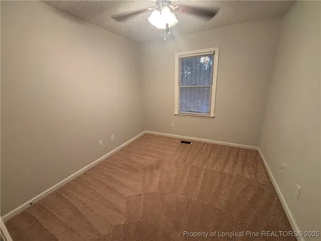 an empty room with a chandelier fan