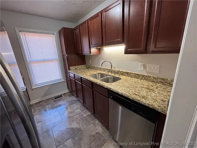 a kitchen with granite countertop sink stove and cabinets