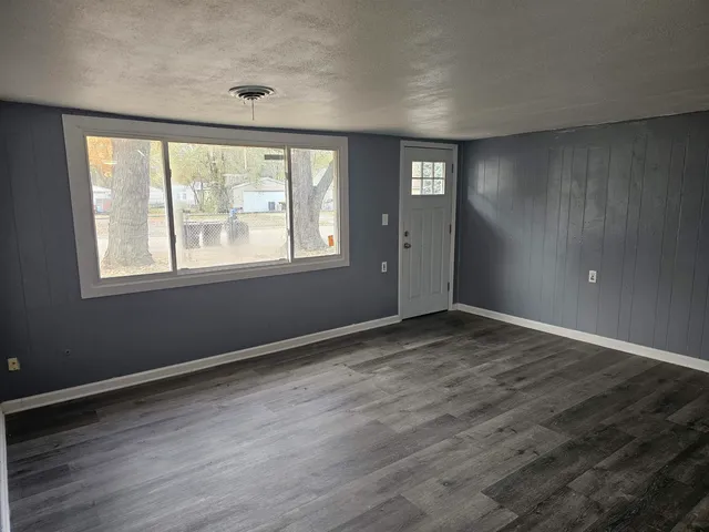 a view of an empty room with wooden floor and a window