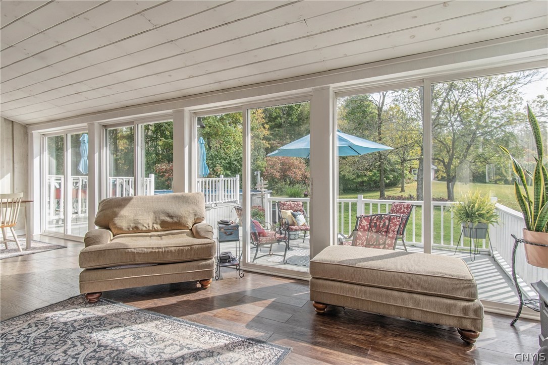 15384 Fuller Road Adams, NY 13606 - Photo 41 of 50 Sunlight streams through expansive glass doors onto rich wood floors beneath a paneled ceiling.