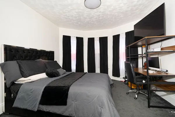 a bedroom with a bed a flat screen tv and gym equipment