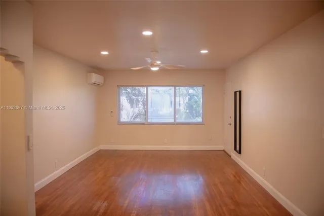 an empty room with wooden floor and window