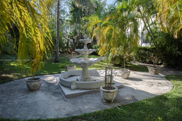 a front view of a house with a yard plants and fountain