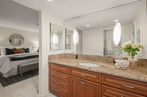a en suite bathroom with a granite countertop sink and a mirror