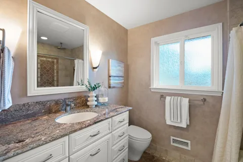 a bathroom with a granite countertop sink toilet and mirror