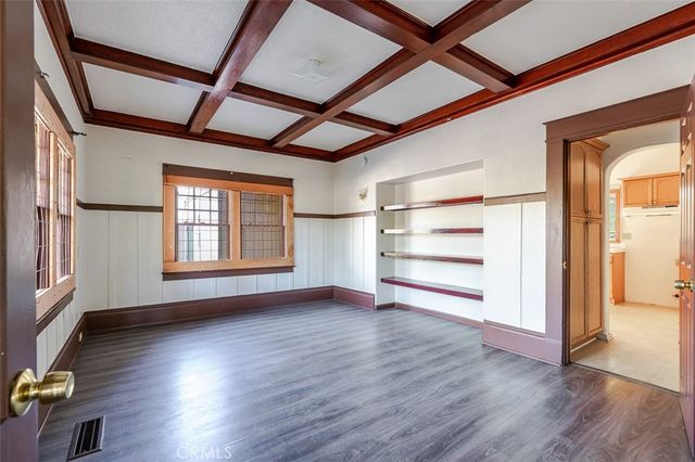 an empty room with wooden floor closet and windows