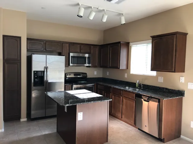a kitchen with kitchen island granite countertop stainless steel appliances a sink stove and refrigerator