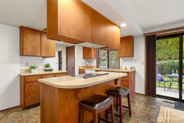 a kitchen with stainless steel appliances kitchen island granite countertop a sink a stove a dining table and chairs