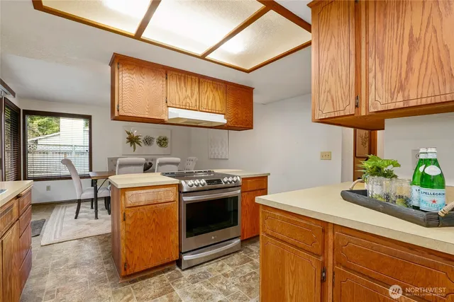 a kitchen with stainless steel appliances granite countertop wooden cabinets a stove a sink and a dishwasher