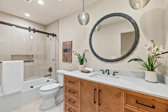 a bathroom with a granite countertop sink a mirror a toilet and a shower