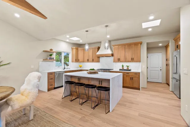 a kitchen with stainless steel appliances kitchen island granite countertop a table chairs sink and cabinets
