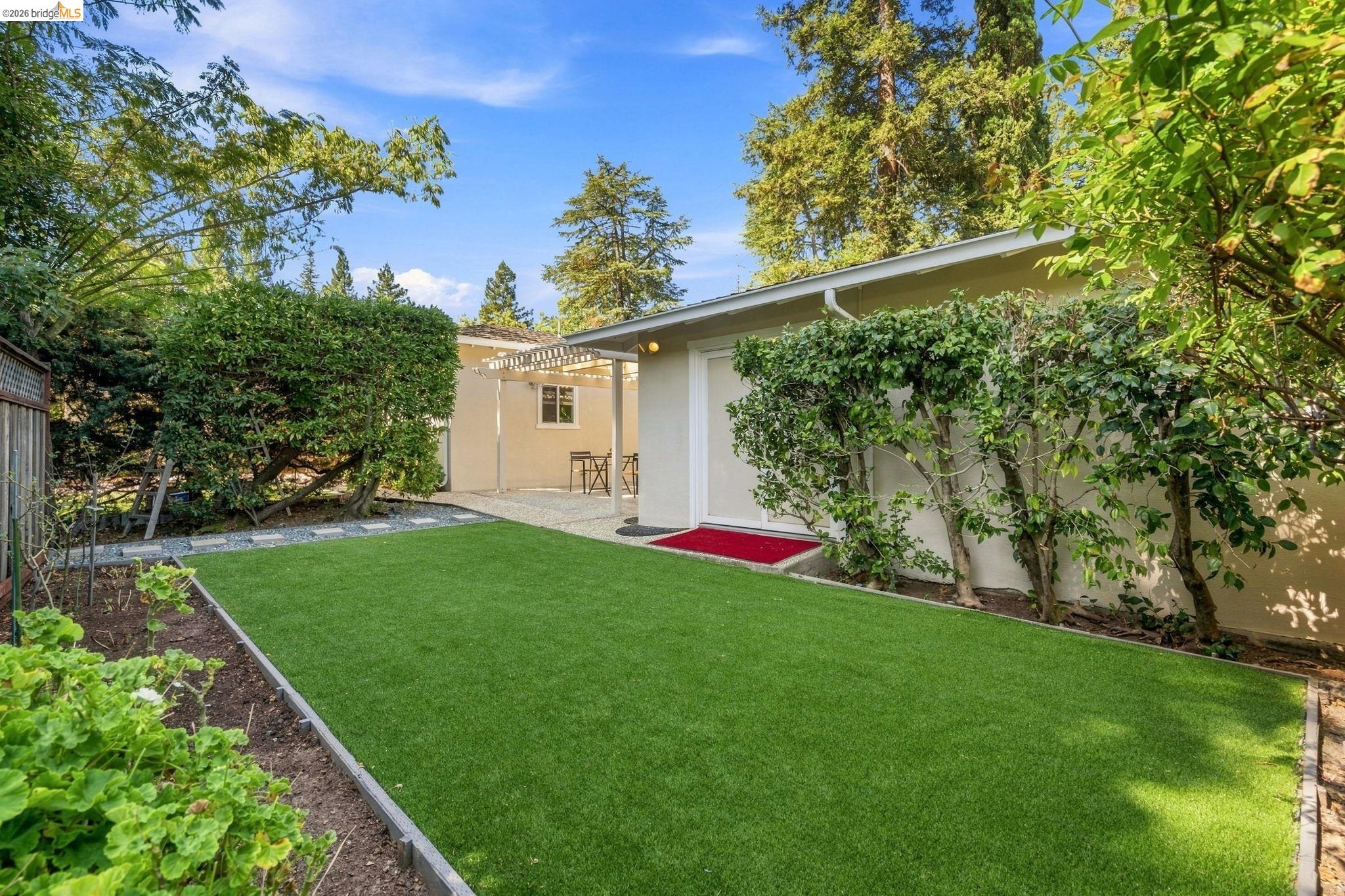 5075 Alhambra Valley Road Martinez, CA 94553 - Photo 41 of 68 Expansive artificial turf lawn, planted borders, and a gravel patio with a pergola