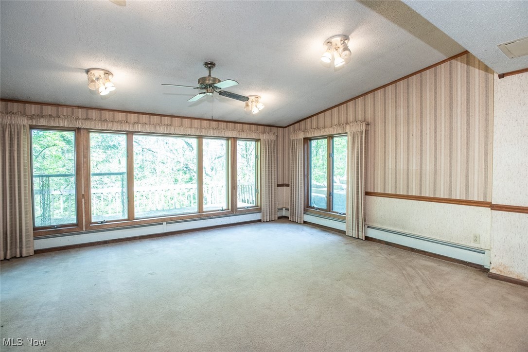 41180 Butternut Ridge Road Elyria, OH 44035 - Photo 44 of 50 Carpeted empty room with a baseboard heating unit, a ceiling fan, a textured ceiling, wallpapered walls, and lofted ceiling