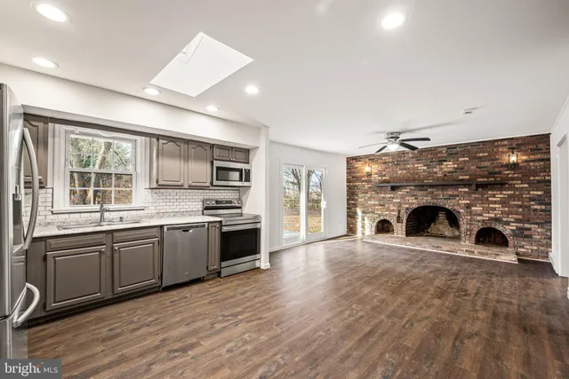 a large kitchen with granite countertop a stove top oven a sink and dishwasher with wooden floor