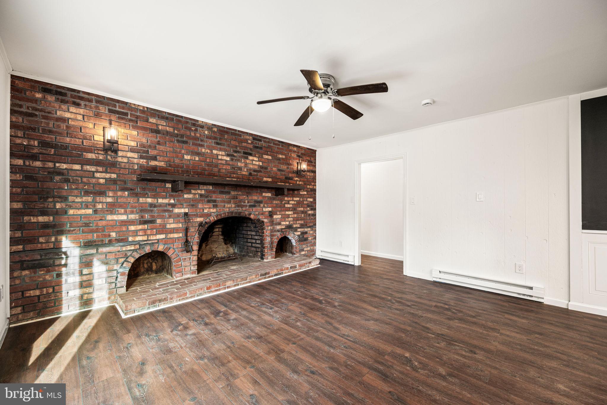 13 Keller Road Cochranville, PA 19330 - Photo 21 of 41 a view of a livingroom with a fireplace a ceiling fan and brick wall