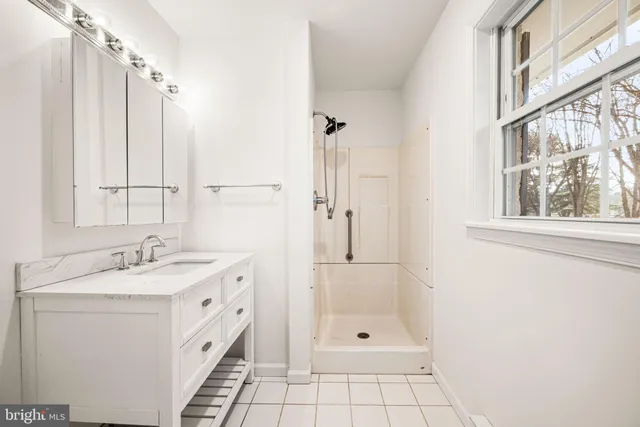 a bathroom with a granite countertop sink a mirror and a shower