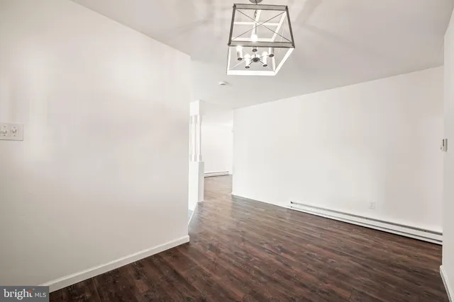 an empty room with wooden floor and chandelier