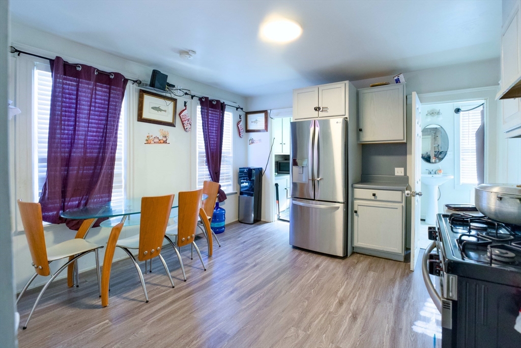 99 Clover Street Worcester, MA 01603 - Photo 7 of 14 a kitchen with stainless steel appliances a refrigerator a stove top oven a dining table and chairs with wooden floor