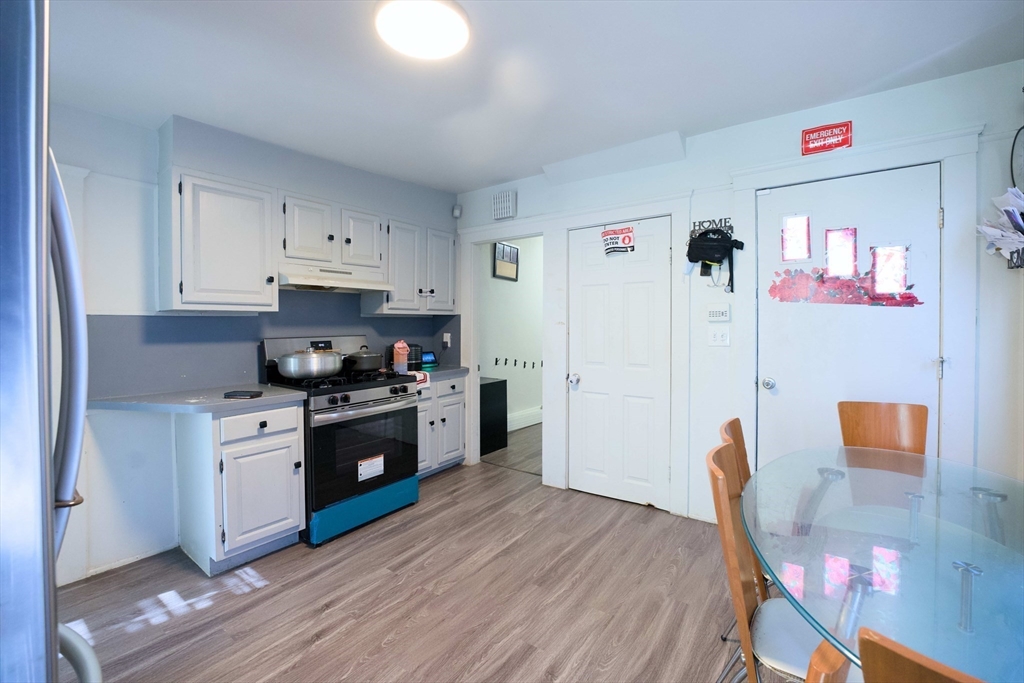 99 Clover Street Worcester, MA 01603 - Photo 8 of 14 a kitchen with stainless steel appliances granite countertop a stove top oven a refrigerator a dining table and chairs with wooden floor