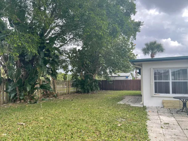 a view of a house with a yard and large tree