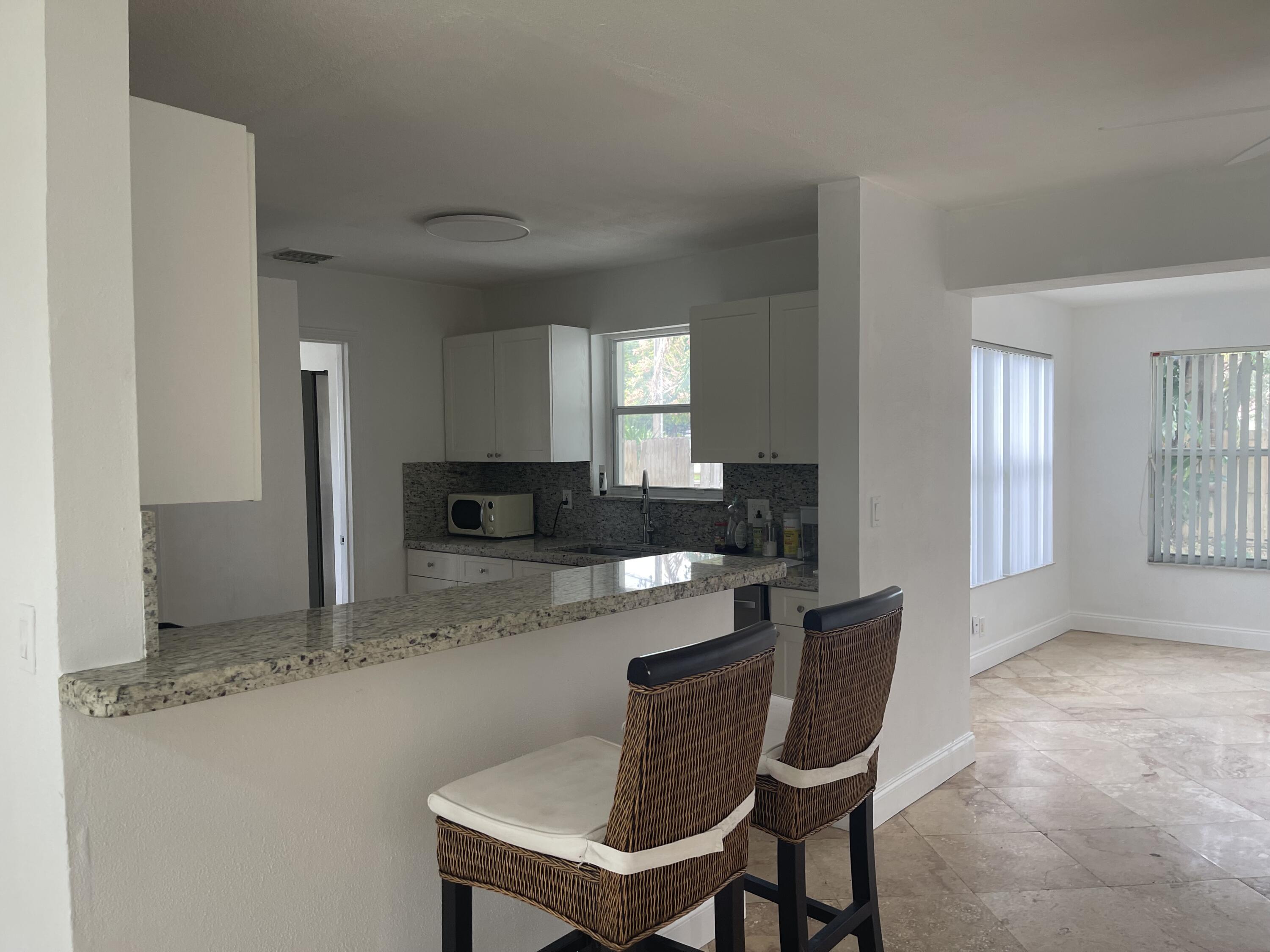 927 West Royal Palm Road Boca Raton, FL 33486 - Photo 5 of 31 a kitchen with stainless steel appliances granite countertop a table and chairs in it