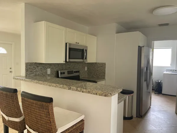 a kitchen with granite countertop a refrigerator and a stove top oven