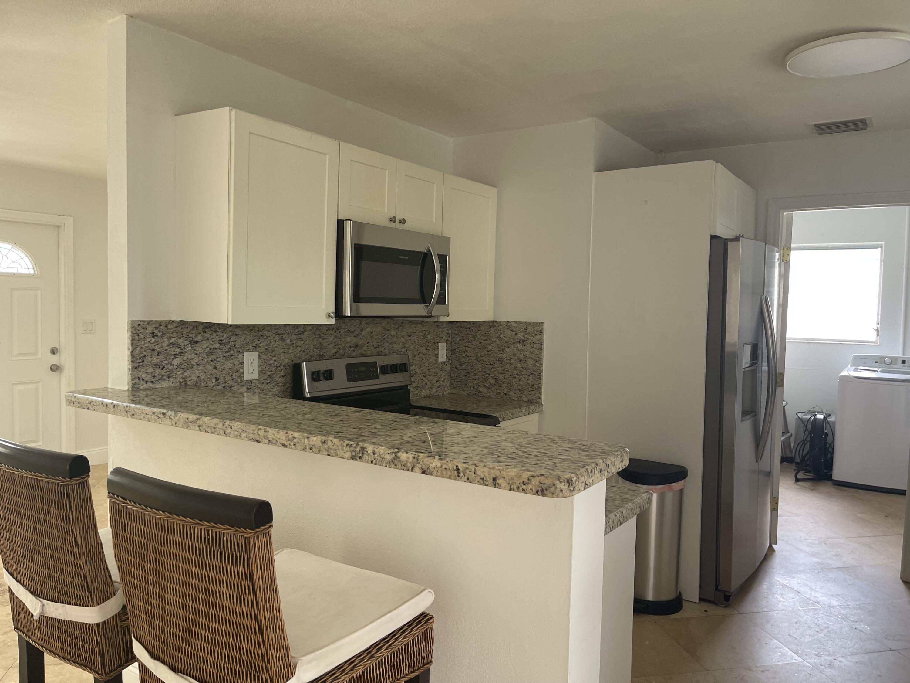 927 West Royal Palm Road Boca Raton, FL 33486 - Photo 6 of 31 a kitchen with granite countertop a refrigerator and a stove top oven