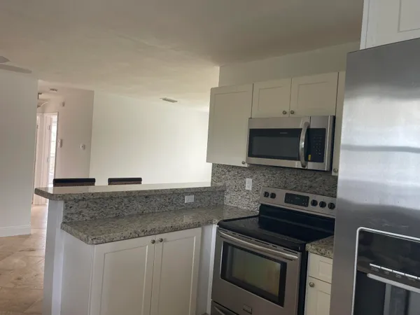 a kitchen with granite countertop a sink stove and microwave