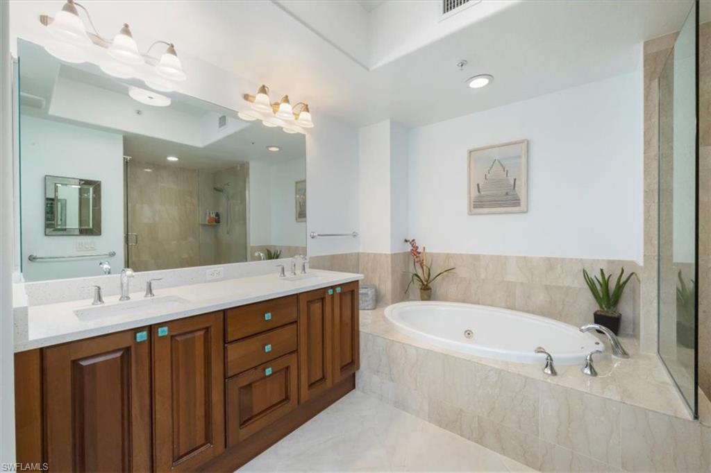965 Sandpiper Street, Unit J107 Naples, FL 34102 - Photo 12 of 30 a bathroom with a tub a sink double vanity and a mirror