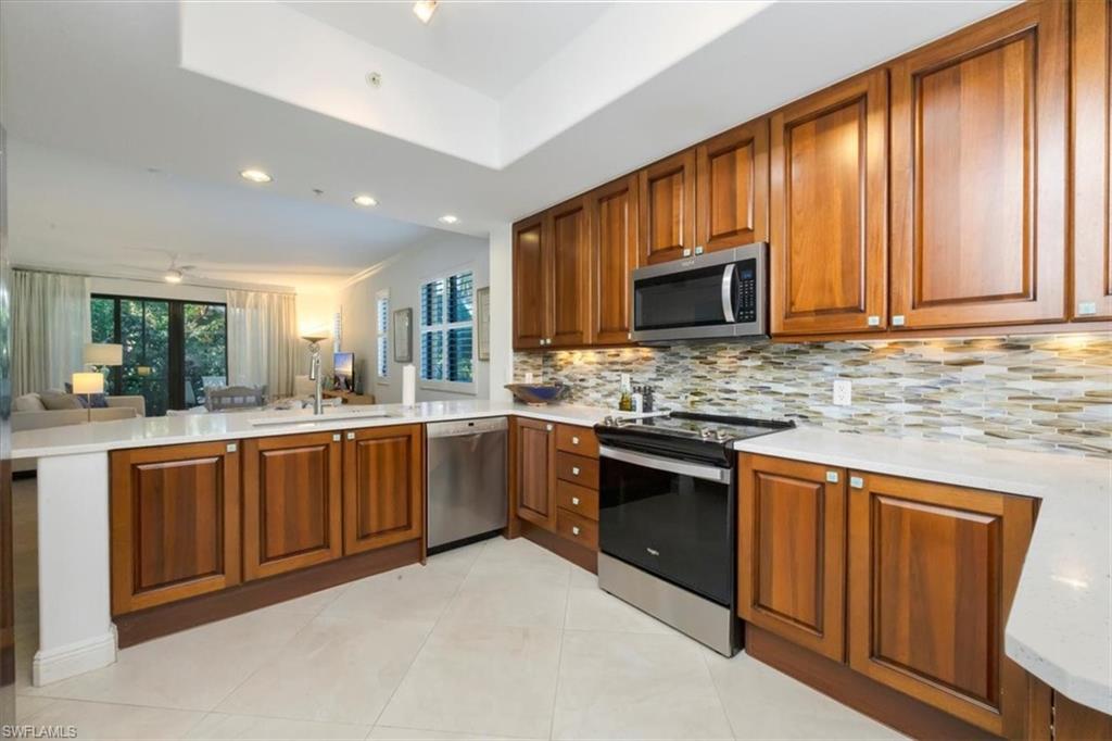965 Sandpiper Street, Unit J107 Naples, FL 34102 - Photo 30 of 30 a kitchen with stainless steel appliances granite countertop wooden cabinets a stove top oven a sink and dishwasher