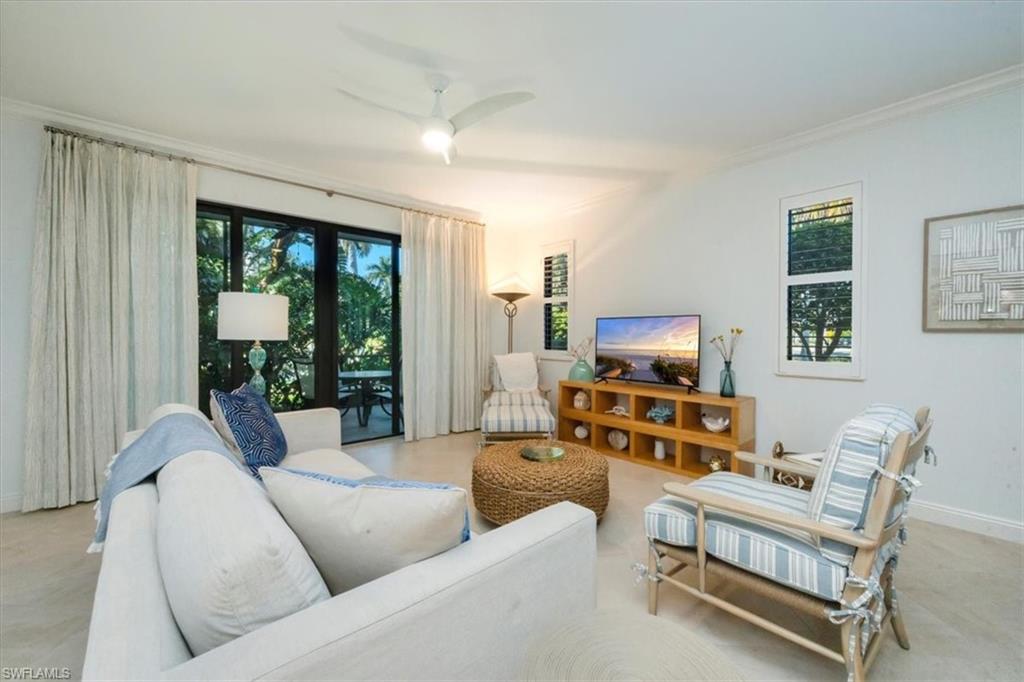 965 Sandpiper Street, Unit J107 Naples, FL 34102 - Photo 8 of 30 a living room with furniture floor to ceiling window and a flat screen tv