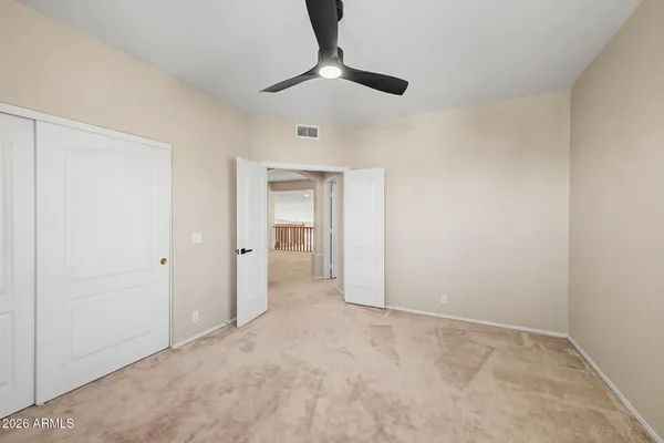 a view of an empty room and chandelier fan
