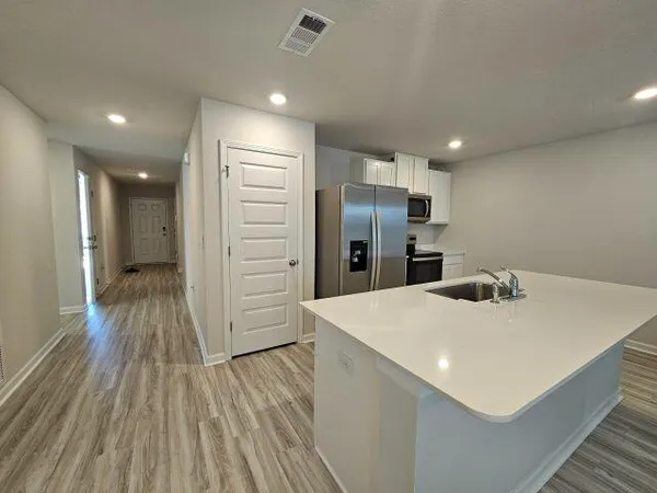 a kitchen with stainless steel appliances a refrigerator and wooden floor