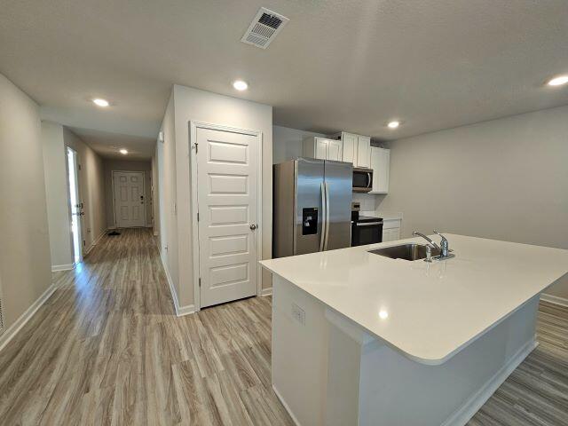 327 Flounder Street Crestview, FL 32539 - Photo 2 of 26 a kitchen with stainless steel appliances a refrigerator and wooden floor