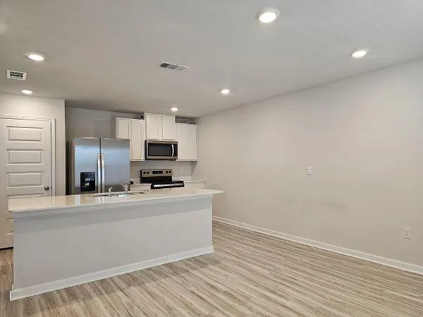 a large kitchen with stainless steel appliances a large counter top a stove and a refrigerator