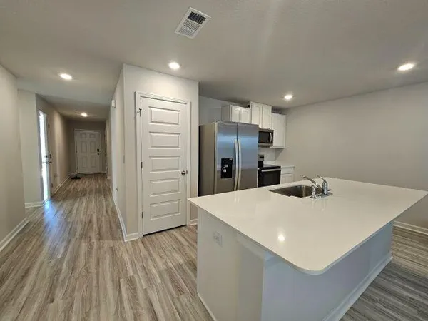 a kitchen with refrigerator and wooden floor
