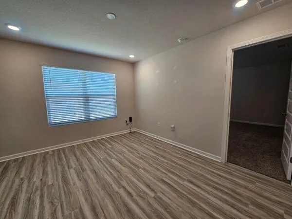 an empty room with wooden floor and windows