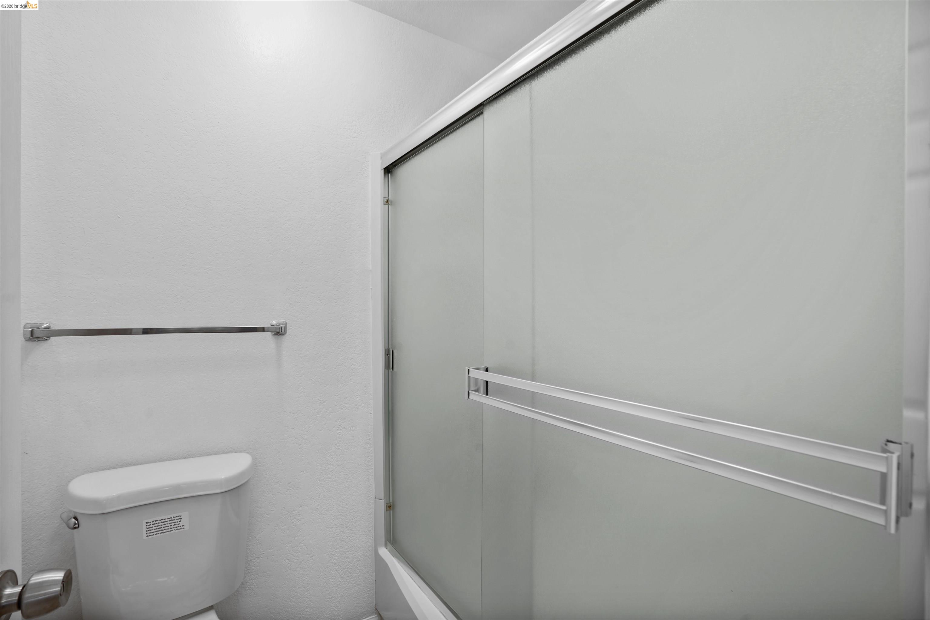 1505 Kirker Pass Road, Unit 214 Concord, CA 94521 - Photo 36 of 55 Bathroom featuring a white toilet, chrome towel bar, and a shower enclosure with frosted sliding glass doors