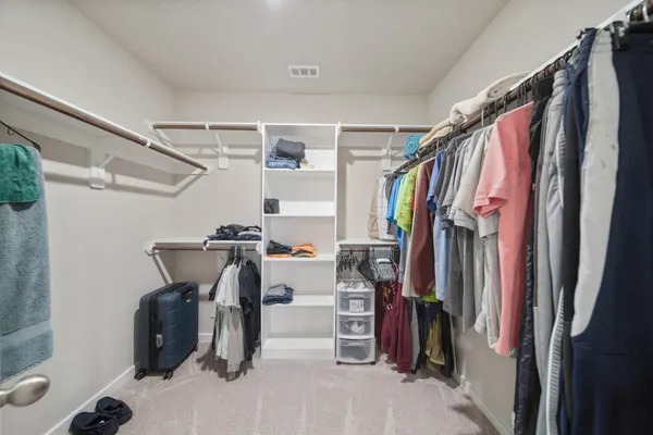 a view of walk in closet with clothes and shoes