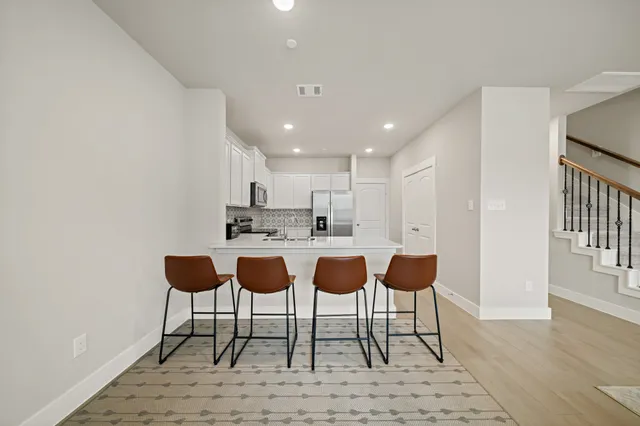 a kitchen with stainless steel appliances kitchen island granite countertop a dining table chairs and a sink