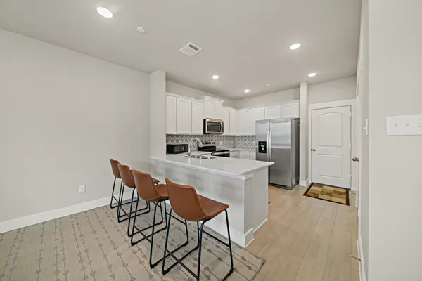 a kitchen with stainless steel appliances granite countertop a sink a stove a refrigerator with a dining table and chairs
