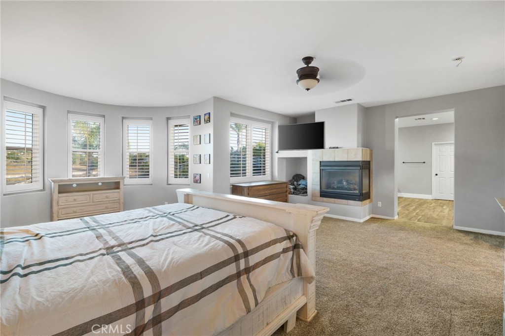 18604 Sunset Knoll Drive Riverside, CA 92504 - Photo 27 of 66 a spacious bedroom with a large bed a flat tv screen and a fireplace