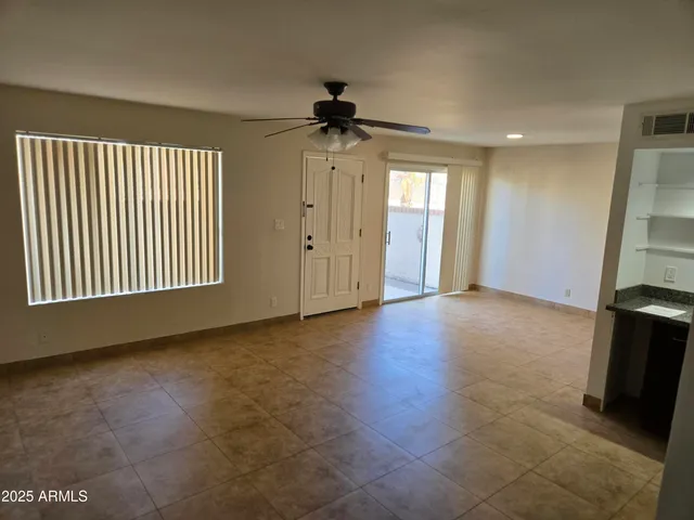 en empty room with windows and ceiling fan