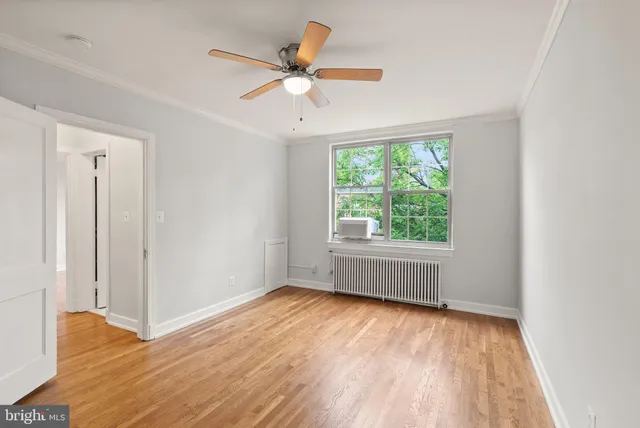 an empty room with wooden floor fan and windows