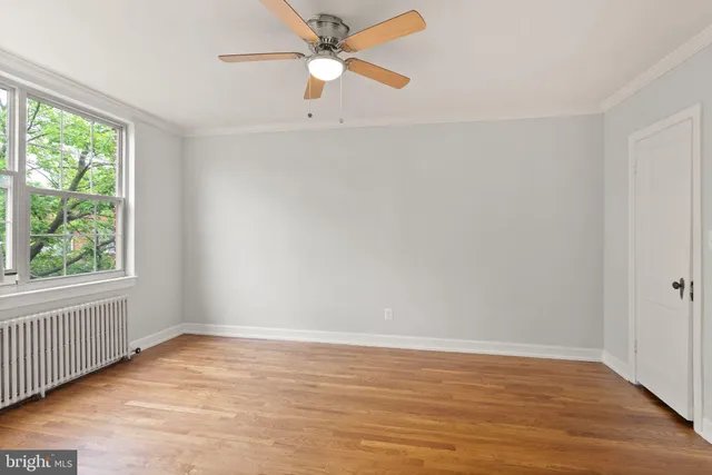 an empty room with wooden floor fan and windows