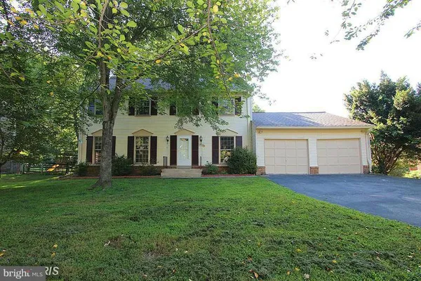 a view of a house with a yard and large trees