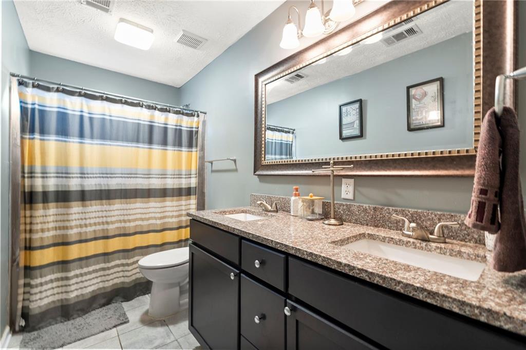 905 Ahearn Court Suwanee, GA 30024 - Photo 23 of 26 a bathroom with a granite countertop sink and a large mirror
