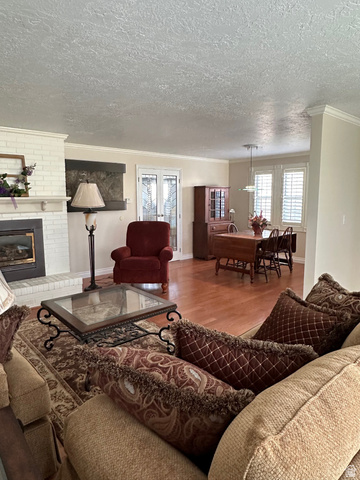 254 Meadow Lane Centerville, UT 84014 - Photo 6 of 34 Open-concept living area featuring wood-finish flooring, a white brick fireplace, and crown molding