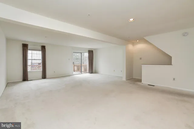 a view of an empty room with windows and closet